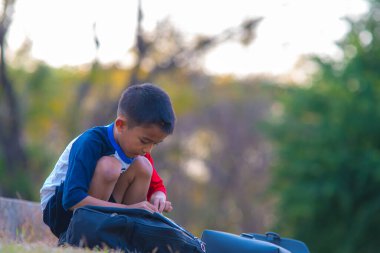 Küçük okul çocuğu açık hava parkında akıllı telefon oyunu oynuyor.