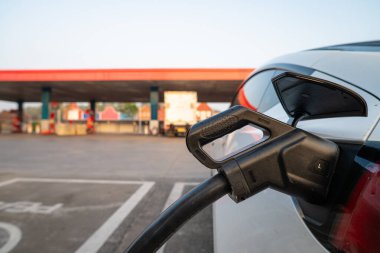 EV şarj kolu elektrik araba istasyonuna bağlı, alternatif ve sürdürülebilir enerjiyle EV araba aküsünü şarj ediyor