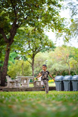 Yeşil çayır çimen parkında koşan küçük anaokulu çocuğu.