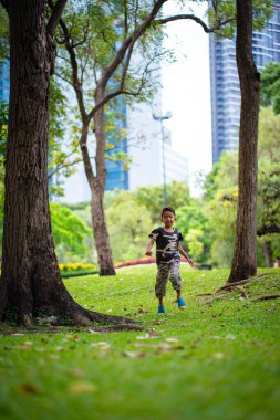 Yeşil çayır çimen parkında koşan küçük anaokulu çocuğu.