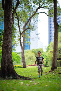Yeşil çayır çimen parkında koşan küçük anaokulu çocuğu.