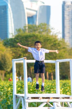 Asyalı okul çocuğu, şehir parkında rahatla, gün batımı, gün batımı, şehir çocuğu.
