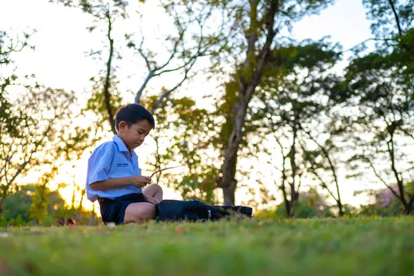 Asyalı okul çocuğu, şehir parkında rahatla, gün batımı, gün batımı, şehir çocuğu.