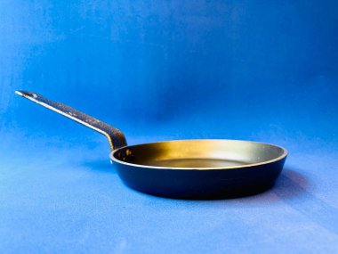 Mavi arka planda kızartma tavası. Küçük kızartma tavası. Mavi arka planda metal kaşık, yemek pişirme konsepti 