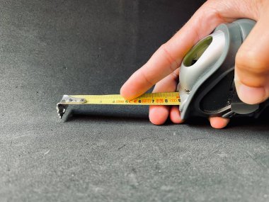 Rulet boyutları ölçer. Doğrusal ölçü işaretli rulet. Bir adamın elinde bir mezura tutarken görüntüyü kapat.. 