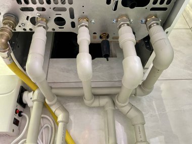 Plastik borular. Gaz kazanı. Kazan boruları. Modern bir evdeki beyaz, sarı ve beyaz boruları kapatın.