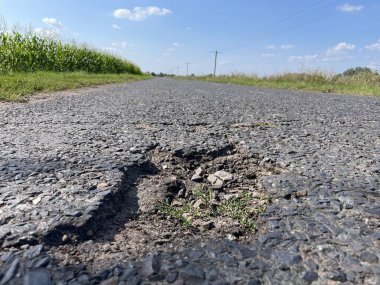 Yoldaki çukurlar ve asfalt taşları. Yoldaki asfalt kaldırım tahrip olmuş. Asfalt yolda tehlikeli bir çukur. Çatlak yol.