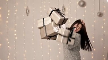 Mutlu Çekici Bir Kız Bir demet hediye kutusu tutuyor, Büyük bir hediye dağı kadının üzerine düşüyor,