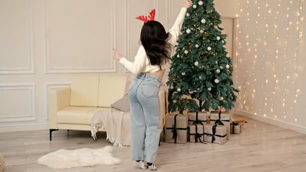 Een Gelukkige Glimlachende Brunette Vrouw Danst Rond Een Kerstboom Met — Stockvideo