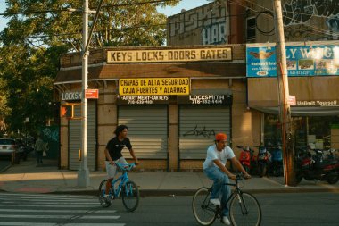 İnsanlar Elmhurst, Queens, New York 'ta Beyazlar Çilingir' in yanından bisikletle geçiyorlar.