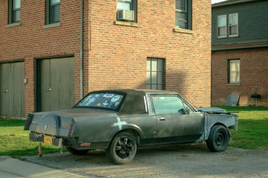 A weathered, sticker-covered car sits parked beside a brick building in Marion, Virginia clipart