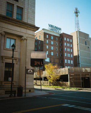 A vintage hotel sign and an insurance building on a quiet street corner, located in Lynchburg, Virginia clipart