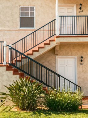 University Heights, San Diego, Kaliforniya 'da siyah parmaklıklı ve yeşillikli sıva dairelerin dış görünüşü