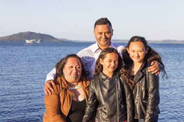 Dışarıda çekilmiş genç bir Maori ailesinin portresi.