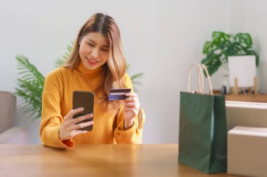 Ev konseptinde çalışan Asyalı kadın, akıllı telefondan online alışverişe kadar kredi kartı verilerini yazıyor..