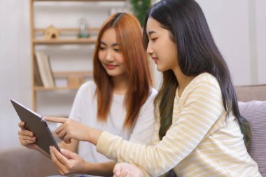 Ev kavramında rahatlayın, LGBT lezbiyen çifti birlikte çalışırken tableti gösterip izliyorlar..