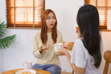 Ev kavramında rahatlayın, LGBT lezbiyen çifti kahve içer ve konuşurken kurabiye yer..