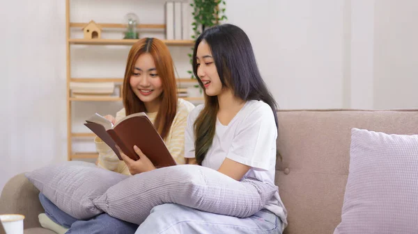 Relax at home concept, LGBT lesbian couple reading and learning holy bible together in living room.