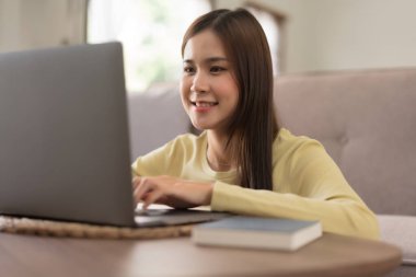 Leisure activity concept, Young woman typing on laptop while sitting to relaxation on the floor.