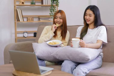 Ev ortamında faaliyet gösteren lezbiyen çift, birlikte film izlerken kahve içip atıştırıyor..