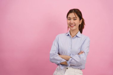 Kadınlar otururken gülümsüyor ve kollarını kapalı pembe arka planda boş bir alanla kavuşturuyorlar..