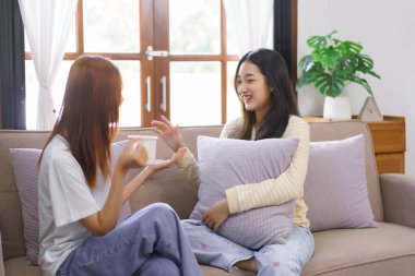 Ev kavramında rahatlayın, LGBT lezbiyen çifti kahve içiyor ve oturma odasında sohbet ediyorlar..