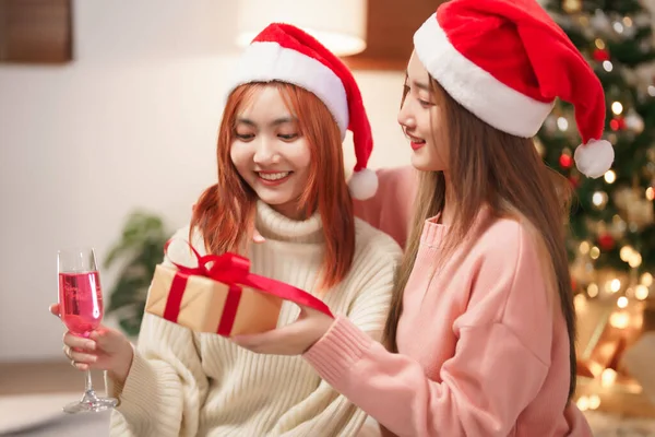 クリスマスのお祝いのコンセプト 友人にクリスマスプレゼントを与えるアジアの女性とシャンパンを飲む — ストック写真