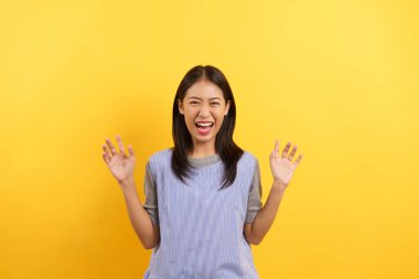 Genç kadınlar sarı arka planda izole edilmiş bir kaplan hayal ederken pençe hareketi ve kükreme yapıyor..