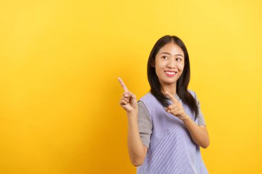 Genç kadınlar, izole edilmiş sarı arka planda boş bir alanı işaret ediyorlar..