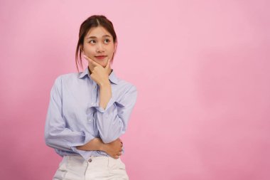 Kadınlar çeneye dokunup işaret ederek pembe arka planda izole edilmiş bir şey düşünürler..