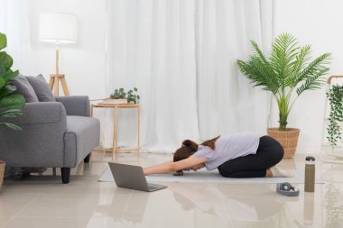 Yoga exercise concept, Asian woman doing yoga with lying in child pose in class online at home.