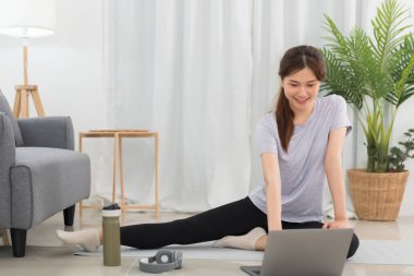 Yoga exercise concept, Young Asian woman doing yoga exercise with tutorial training online at home.