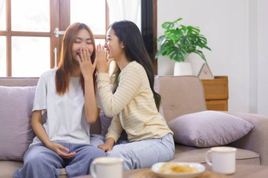 Ev konseptinde faaliyet, lezbiyen bir kadın kız arkadaşıyla el ele fısıldaşırken ağzını kapatıyor..