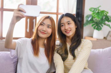 Ev kavramındaki etkinlik, LGBT lezbiyen çifti gülümsüyor ve akıllı telefonu birlikte selfie çekmek için kullanıyorlar..