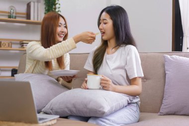 Ev konsepti etkinliği, lezbiyen kadın kahve içiyor ve oturma odasında kız arkadaşına atıştırmalık veriyor..