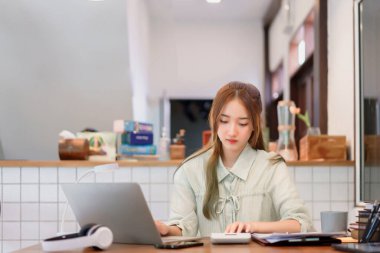 Uzaktan çalışma kavramı, kadın girişimci birlikte çalışma alanındaki dizüstü bilgisayarda hesap makinesi ve yazma verisi kullan.