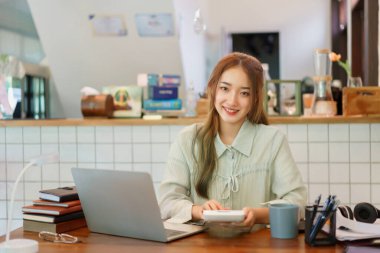Ortak çalışan uzay ofisi kavramı, kadın girişimci proje bütçesini hesaplamak için hesap makinesi kullanıyor.