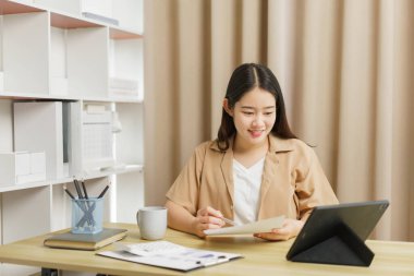 Çevrimiçi yaşam tarzı konsepti Çalışan bir kadın Belge ve tableti hakkında bazı detayları kontrol ediyor