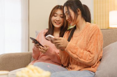 Friendship concept, LGBT lesbian couple surfing social media on smartphone to relaxation together.