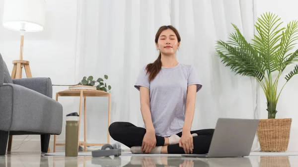 Yoga exercise concept, Young Asian woman with close eyes and meditation before yoga exercise online.