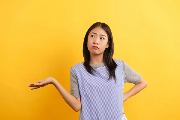 Young women making confused face and open one hand to asking why on isolated yellow background.