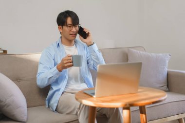 Home office, Businessman drinking coffee in the morning while working and talking on smartphone.