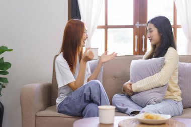 Ev kavramındaki hareketlilik, LGBT lezbiyen çifti kahve içiyor ve oturma odasında sohbet ediyorlar..