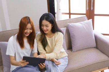 Ev kavramında rahatlayın, LGBT lezbiyen çifti birlikte çalışırken tableti gösterip izliyorlar..