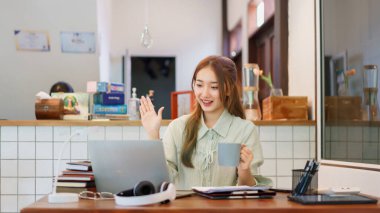 Remote work concept, Woman entrepreneur drinks coffee and greeting on video call in coworking space.