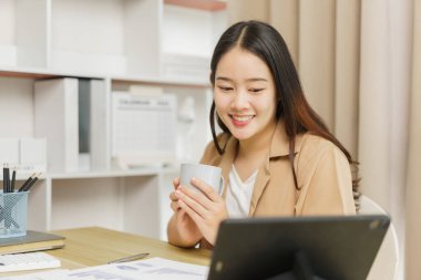 Çevrimiçi yaşam tarzı konsepti. Tablet hakkında bilgi okurken elinde bir fincan kahve tutan bir kadın işçi.