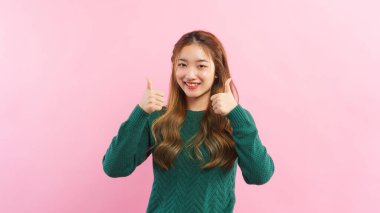 Young women thumb up with both hands and smiling with happiness isolated on pink background.