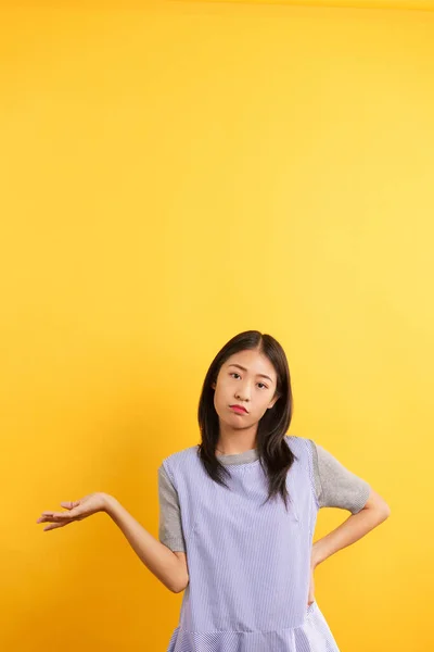 Young women making confused face and open one hand to asking why on isolated yellow background.