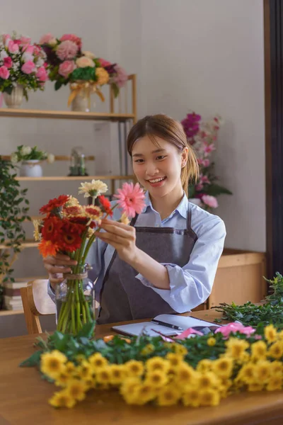 Çiçekçi konsepti, çiçekçi kadın çiçekçi çiçekçide müşteriler için cam vazoda renkli gerberalar düzenledi..
