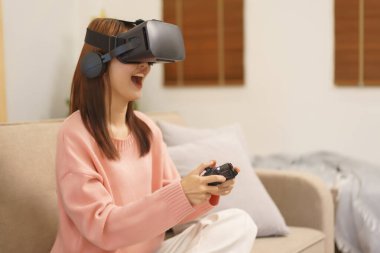 Lifestyle at home concept, LGBT lesbian women wears VR goggles and play game with joystick console.